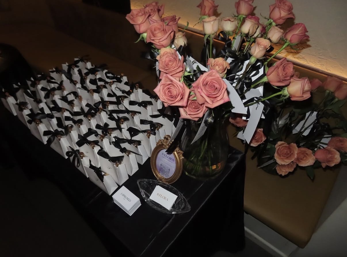 Gift bags tied with black ribbon beside pink roses